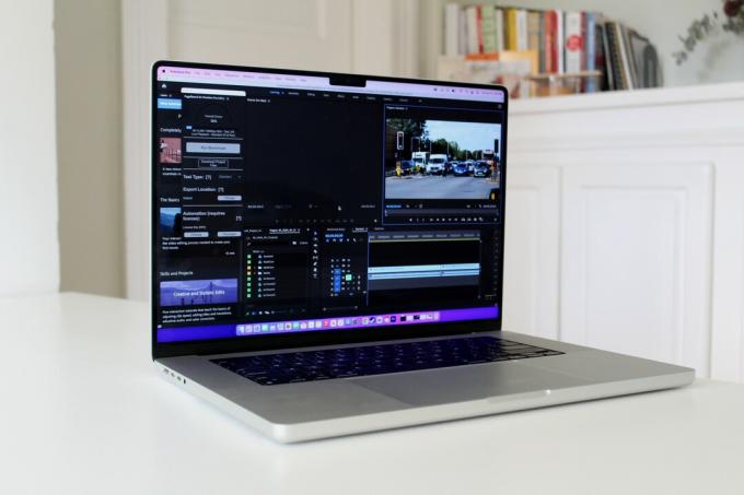 Apple MacBook Pro er et hvitt bord med bøker på en hylle i bakgrunnen.