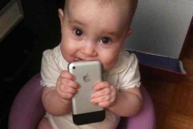 Tyttövauva pitelee 2007 iPhonea suussaan.