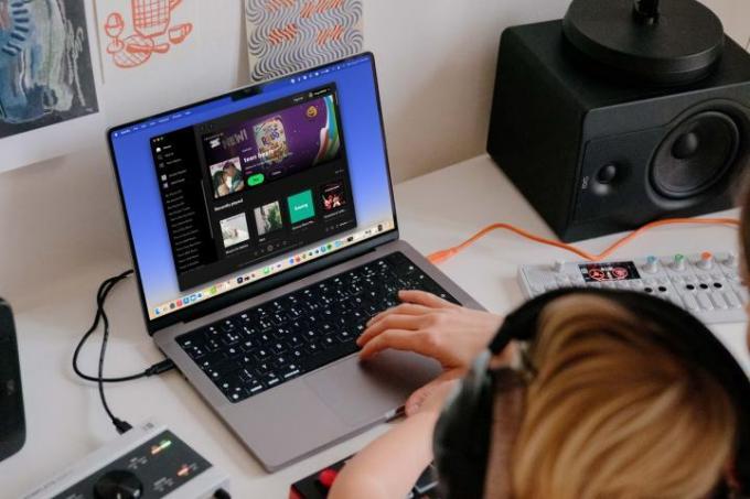 Люди в навушниках слухають Spotify на MacBook.