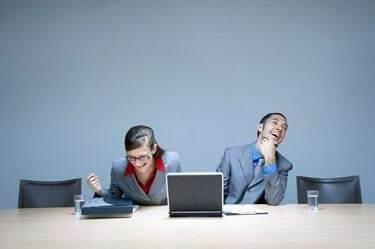 Femme d'affaires et homme d'affaires assis au bureau avec un ordinateur portable, riant