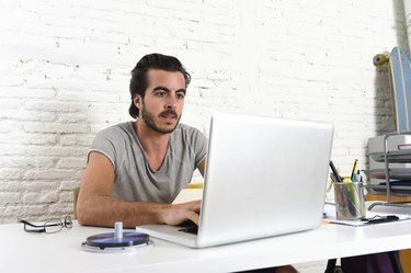 hipsterski študent ali poslovnež, ki dela s prenosnim računalnikom v pisarni