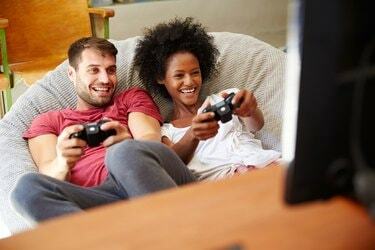 زوجين شابين في ملابس النوم يلعبان لعبة فيديو معًا