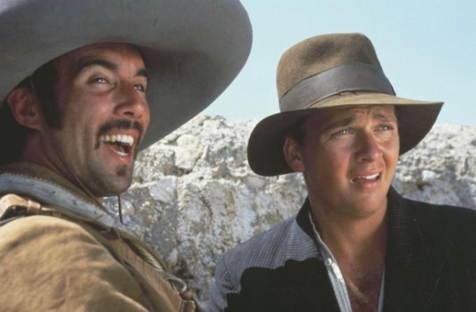 Indiana Jones y un amigo se paran uno al lado del otro y se miran.