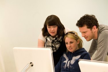 Skupina tří studentů grafického designu spolupracujících na počítači mac.