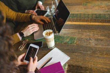 Entrega la tableta del teléfono inteligente portátil con café en la cafetería de moda