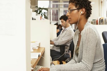 Trabalhadora de escritório na mesa, usando fones de ouvido