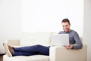 Mies istuu sohvalla digitaalisella tabletilla