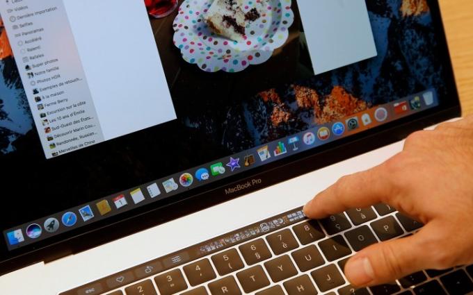 Prim-plan al unei persoane care folosește un Macbook Pro Touch Bar.