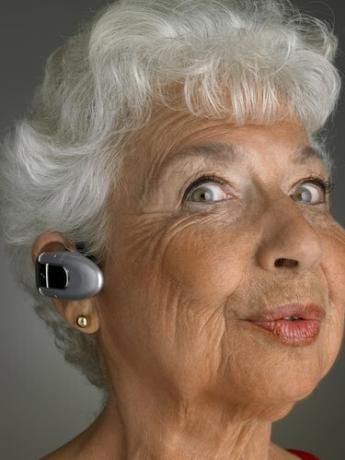 Vyresnio amžiaus moteris, dėvi „Bluetooth“, traukia veido išraišką, portretas, stambiu planu