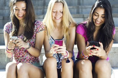 tři dívky chatující se svými chytrými telefony