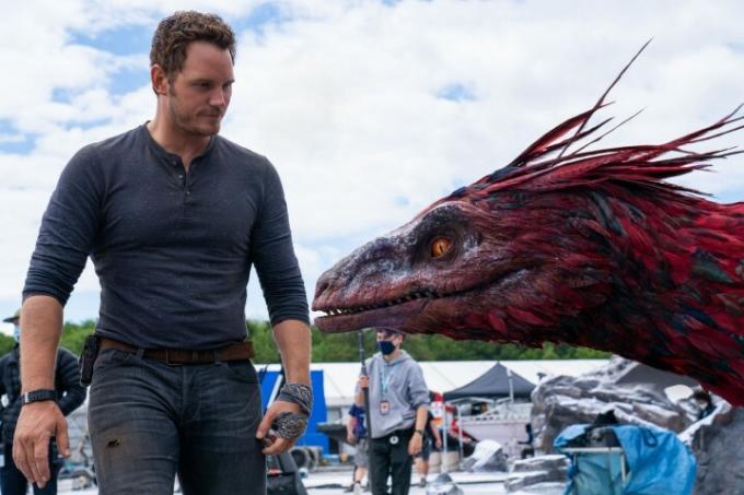 Chris Pratt가 Jurassic World Dominion 세트장에서 파이로랩터의 머리 모델 옆에 서 있습니다.