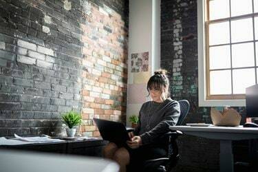 Δημιουργική επιχειρηματίας που χρησιμοποιεί φορητό υπολογιστή στο γραφείο