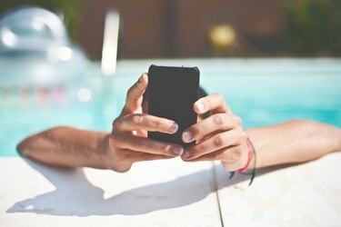 Close-up de uma mão segurando um telefone celular na piscina