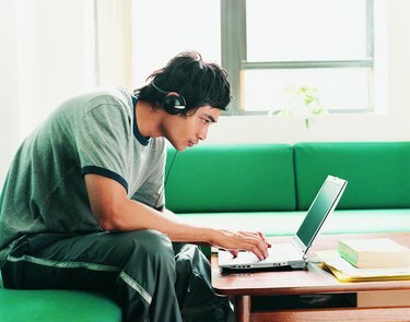 طالب آسيوي يستخدم الكمبيوتر المحمول في المنزل