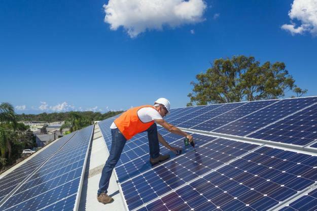 homme installant des panneaux solaires