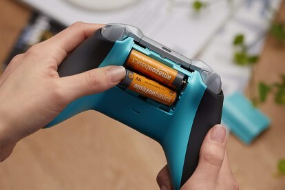 Pilhas AA AmazonsBasics sendo inseridas em um controlador de jogo.