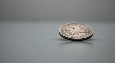 Novčić američkog dolara na rubu, vrti se, bijela pozadina, zamrznut u pokretu