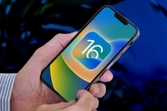 A férfi egy iPhone 13 Pro készüléket tart a képernyőn iOS 16 logóval.