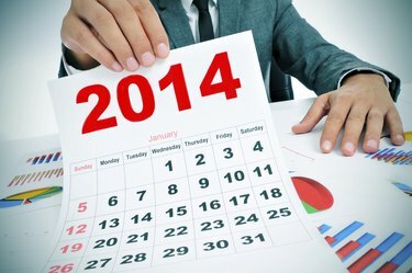 mężczyzna w garniturze z wykresami i kalendarzem na 2014 rok