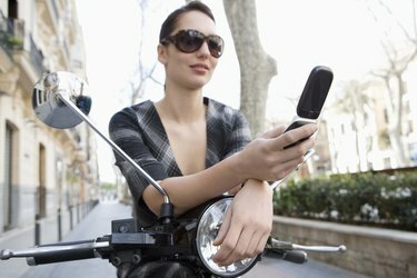 Жена на мотопед с мобилен телефон