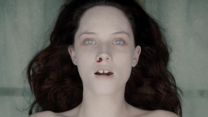 Mrtvá žena na desce s krví tekoucí z nosu v The Autopsy of Jane Doe. 