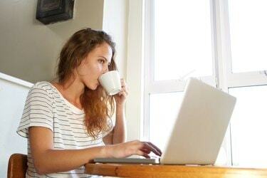 Mujer joven que trabaja en la computadora portátil y tomando café