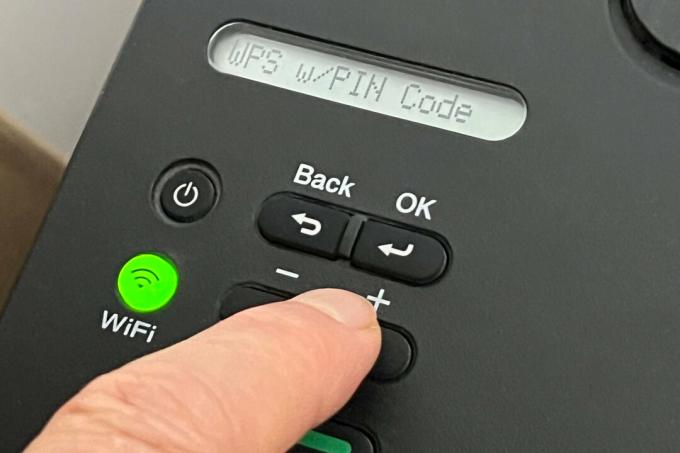 Ein Finger navigiert durch die Menüs eines Druckers, um die WPS-PIN-Einstellung zu finden.