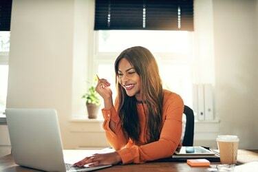 Sonriente joven empresaria trabajando en un portátil en casa