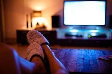 Homme mettant les pieds en l'air et regardant la télévision