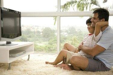 Πλαϊνό προφίλ ώριμου άνδρα με τον γιο του (8-9) να παρακολουθεί τηλεόραση