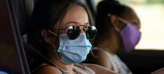 Två flickor bär masker när de sitter i en bil i Sick.