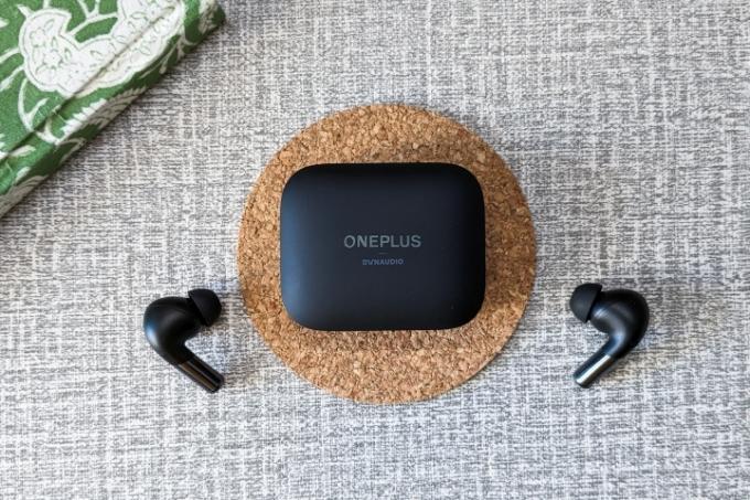 OnePlus Buds Pro 2 svart fodral på en korkunderlägg och svarta öronsnäckor på en vit och grå bordsskiva.