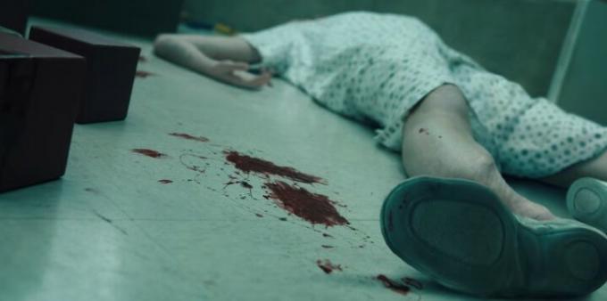 기묘한 이야기 ​​시즌 4의 한 장면에서 실험실 바닥에 부서지고 피투성이가 된 시체가 놓여 있습니다.