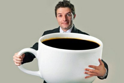 kava ni rakotvorna pregrete pijače so mlad srečen poslovnež, ki drži smešno ogromno in preveliko skodelico črne 15