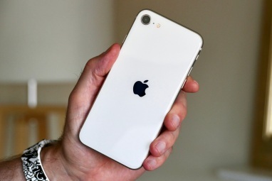 Apple iPhone SE (2022) laikomas vyro rankoje.