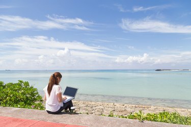 海沿いでPCを操作する若い女性