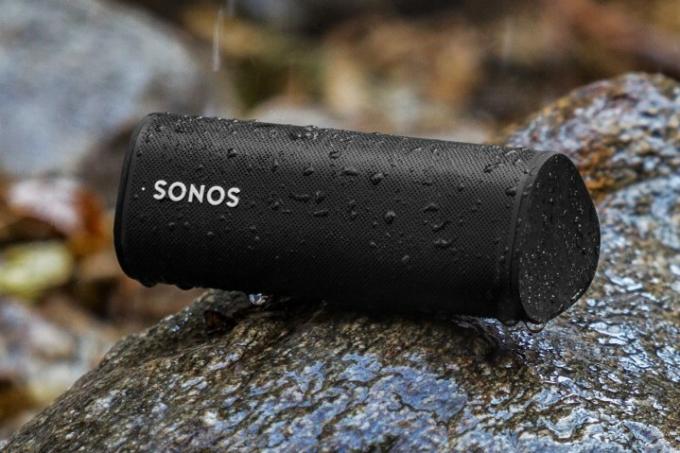 Sonos Roam SL в черном цвете на дождливой скале на открытом воздухе.