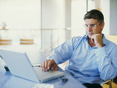 verslininkas, naudojantis nešiojamąjį kompiuterį biure