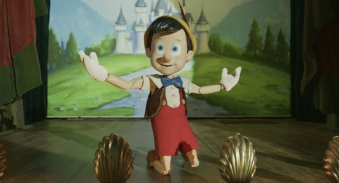Pinokis atsiklaupia ant scenos scenoje iš 2022 m. gyvo veiksmo filmo.
