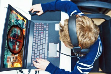 Dječak igra video igrice na igraćem računalu dok nosi slušalice