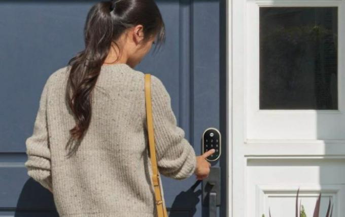Pessoa usando uma trava inteligente na porta da frente.