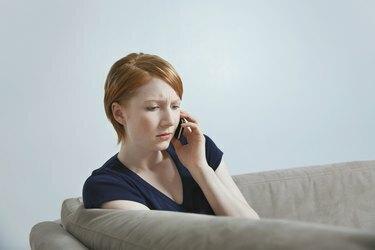 امرأة تتحدث على الهاتف المحمول على الأريكة