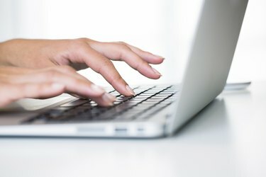 Mani di donna che digitano sulla tastiera di un laptop