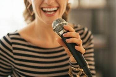 Nahaufnahme auf junge Frau, die mit Mikrofon in Loft-Wohnung singt?