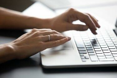 Cerrar manos femeninas escribiendo en el teclado del portátil