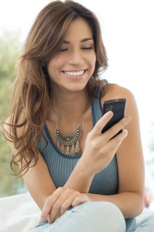 Женщина улыбается и держит мобильный телефон