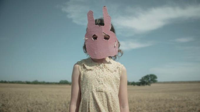 O fată care poartă o mască de iepure stă în Run Rabbit Run.
