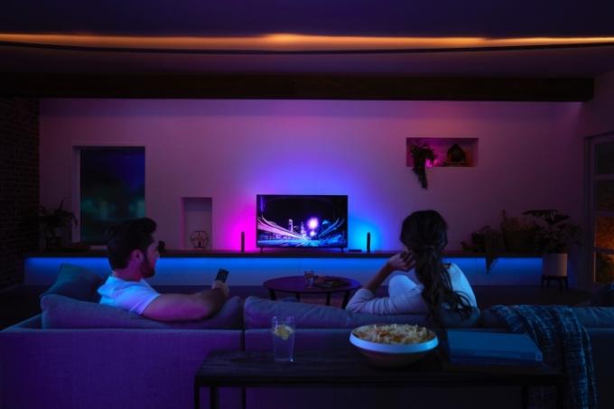 Un bărbat și o femeie într-o sufragerie luminată de o cutie de sincronizare Philips Hue.