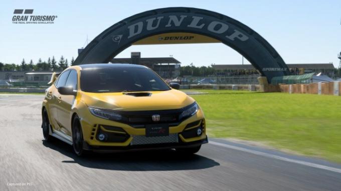 Sebuah Honda Civic Type R balapan di trek Gran Turismo 7 yang disponsori oleh Dunlop.