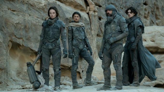 Filmo „Dune“ aktoriai stovi Arrakio dykumoje filmo scenoje.